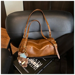 Detailed close-up of brown vintage cylinder bag leather texture with cute bear charm