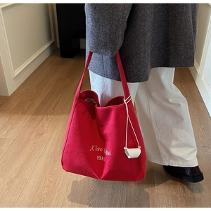 Dettaglio della borsa tote in tela rossa con ricamo bianco e accessorio in pelle