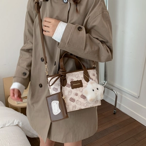 Detail of cartoon printed tote bag featuring a star charm and mini coin pouch accessory