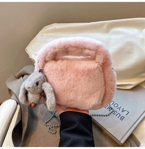 Close-up of pink faux fur handbag with a cute rabbit pendant and a metal chain strap