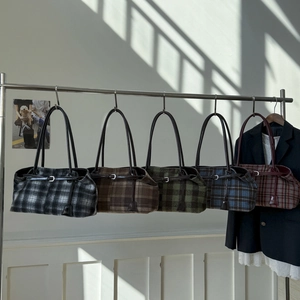Detail of five plaid wool underarm bags in various colors on a metal rack