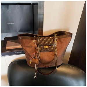 Detail view of large brown tote bag showing quilted texture and gold metal chain strap