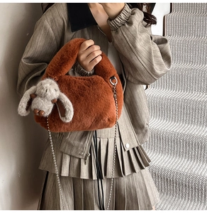 Close-up of brown plush faux fur bag with metallic chain strap and cute rabbit pendant
