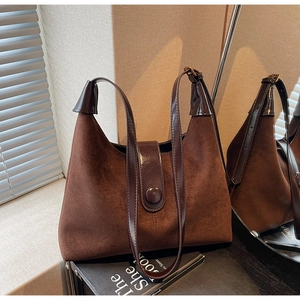 Detailed texture of retro brown suede handbag with glossy leather strap and metal buckle