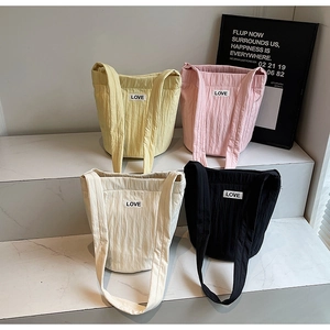 Detailed view of quilted tote bags in four colors with LOVE patch on marble steps