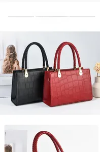 Detail showing red and black crocodile textured handbags with woven top handles and gold hardware
