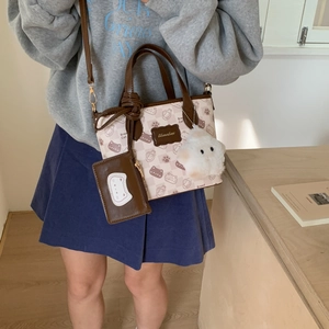 Detail view of canvas bucket bag featuring cute cat prints and a plush cat charm accessory