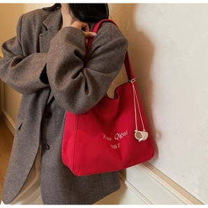 Dettaglio della borsa tote in tela rossa con ricamo bianco e ciondolo rotondo