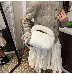 Detail of plush off-white handbag featuring a cute grey bunny charm and silver chain strap