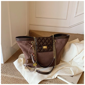 Close-up of vintage brown suede tote with diamond quilting and gold twist lock