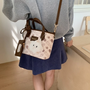 Detail of cartoon tote bag with brown leather handles and plush cat charm