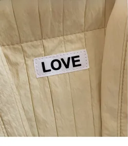 Detail of beige quilted tote bag fabric with vertical pleats and LOVE patch