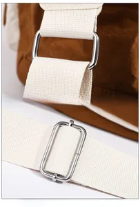 Detail of adjustable woven shoulder strap and polished silver D-ring on the brown nylon bag