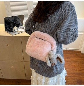 Detailed close-up of a pink fuzzy faux fur crossbody bag with silver chain and bunny charm