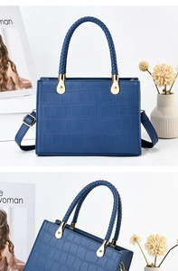 Detail of blue crocodile pattern handbag featuring woven handles and gold metal hardware