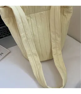 Close-up of pleated yellow tote bag featuring LOVE label and wide shoulder strap