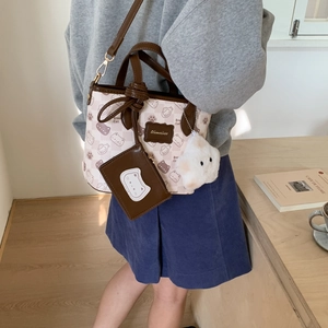 Detail of beige cartoon cat tote bag with Bread Cat print and star plush pendant charms