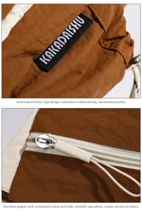 Detail view of the nylon bag showing the logo embroidery and smooth metal zipper with cord
