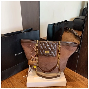 Detail view of brown matte tote bag featuring diamond pattern flap and gold chain strap