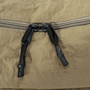 Détail du sac bandoulière en nylon vert montrant les doubles fermetures éclair durables
