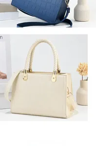 Detail of crocodile embossed leather handbag with woven handles and gold hardware