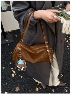 Detail of dark brown vintage Boston bag with adjustable straps and a cute teddy bear charm