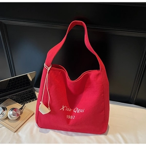 Dettaglio della borsa tote in tela rossa con ricamo bianco e ciondolo accessorio per borsa