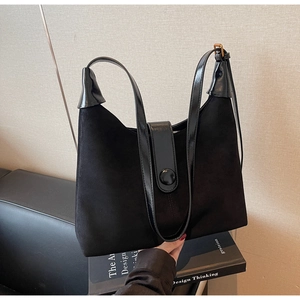 Detail of black suede and patent leather shoulder bag with buckle closure