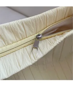 Detail of light beige pleated fabric texture with silver metal zipper on a bucket bag