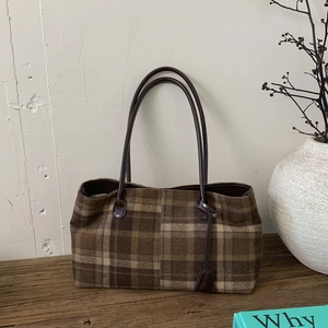 Detailed macro view of vintage brown plaid tote bag with faux leather strap and tag