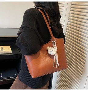 Caramel brown large capacity tote bag worn over the shoulder with plush bear charm