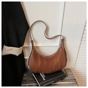 Close-up of brown pleated crescent bag with matte texture and adjustable strap