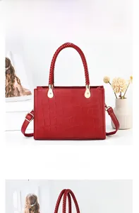 Detailed view of red crocodile-embossed handbag with woven handle and gold hardware