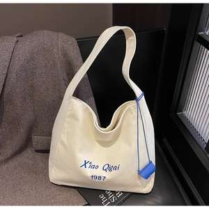 Dettaglio della borsa tote in tela con testo ricamato blu e mini pochette blu accessorio