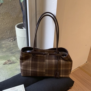Close-up of large plaid checkered tote bag with brown leather handles for daily commute
