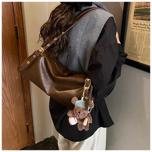 Detail of vintage brown PU leather tote bag with cute bear charm and adjustable strap