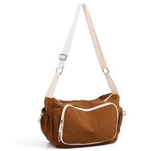 Detail of brown nylon travel bag featuring contrast cream strap and drawstring side pocket