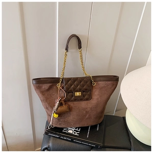 Close-up of brown suede tote bag with diamond-quilted flap and gold twist lock