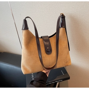 Detail of retro shoulder bag showing suede texture and polished dark brown strap contrast