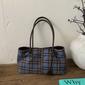Detailed view of the blue and brown plaid wool tote bag on a rustic wooden table