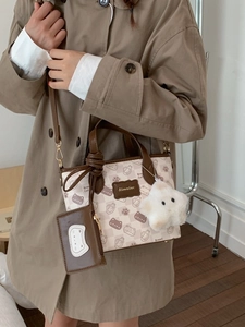 Beige cartoon cat print hobo bag with mini card holder and plush star charm on a model