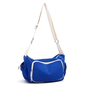 Detailed view of blue nylon crossbody bag featuring large front pocket and side drawstring slots