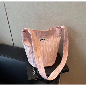 Detail of light pink pleated bucket bag featuring a LOVE label on black design book