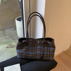 Detail of blue and brown checkered tweed tote bag with slim dark brown leather straps
