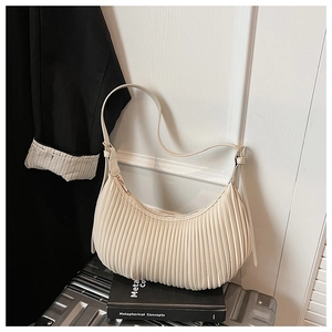 Detailed close-up of beige pleated crescent bag on a minimalist urban lifestyle background