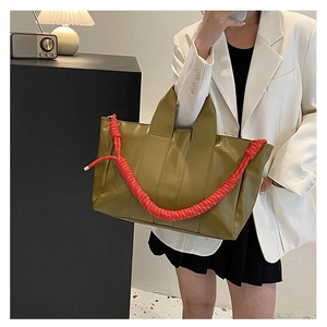 Dettaglio della borsa tote verde oliva con tracolla decorativa rossa a trama a spirale
