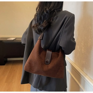 Detail view of large round buckle on a vintage brown suede hobo bag with a dark leather strap