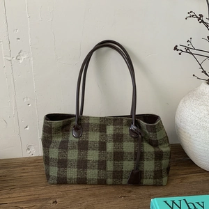 Detailed view of green plaid wool tote bag with leather straps and rustic accessories