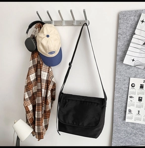 Moderna borsa a tracolla nera con abbigliamento casual su un gancio a muro minimalista