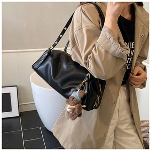 Detail of black PU leather cylinder shoulder bag with cute teddy bear charm